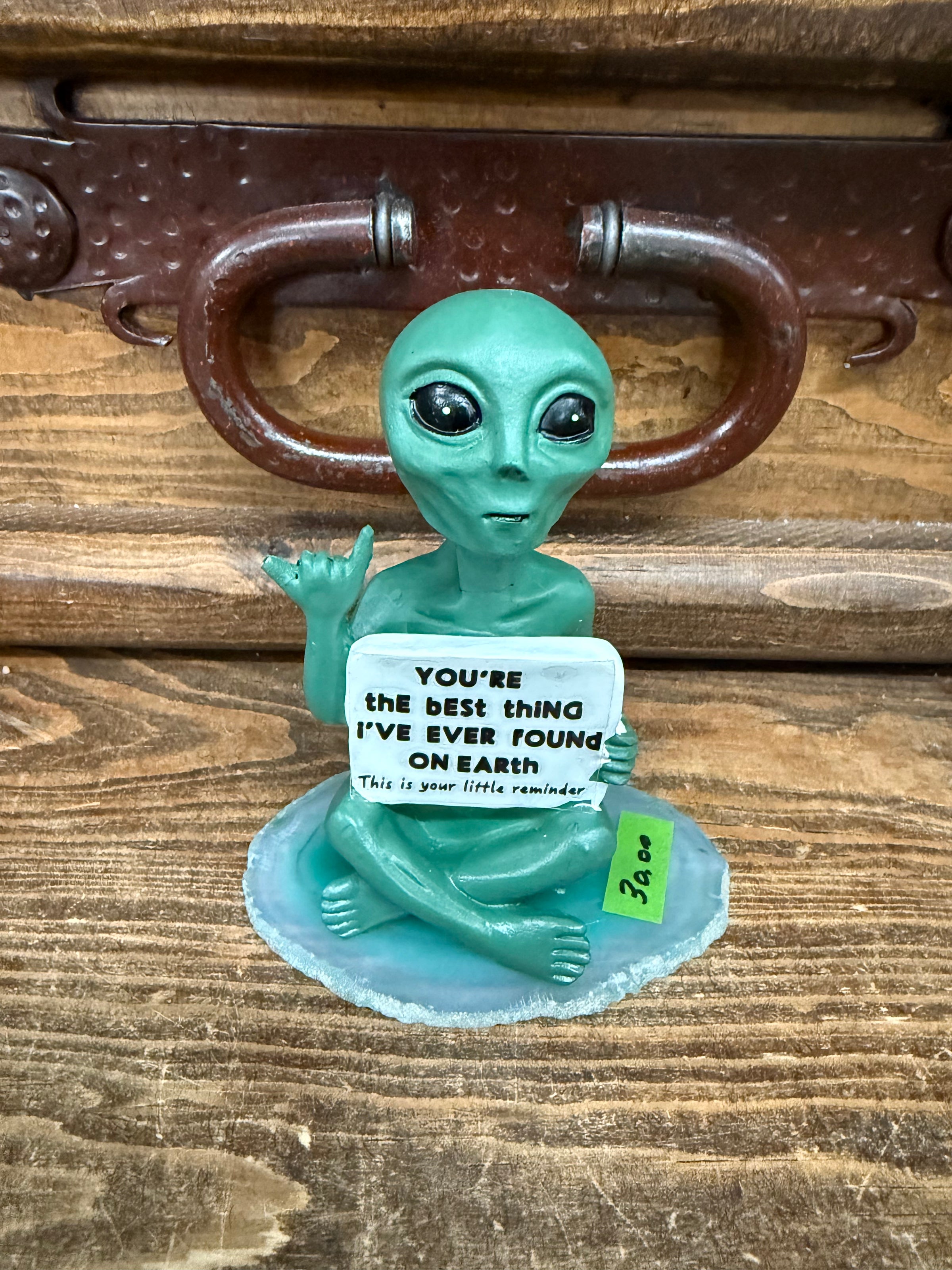 Resin alien sitting on agate slab